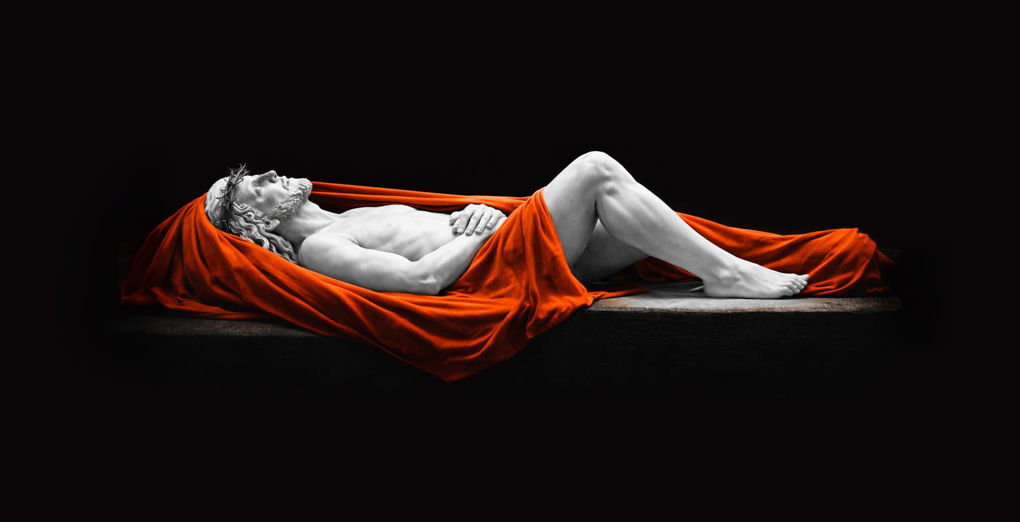 A figure draped in a crimson shroud resting in darkness.
